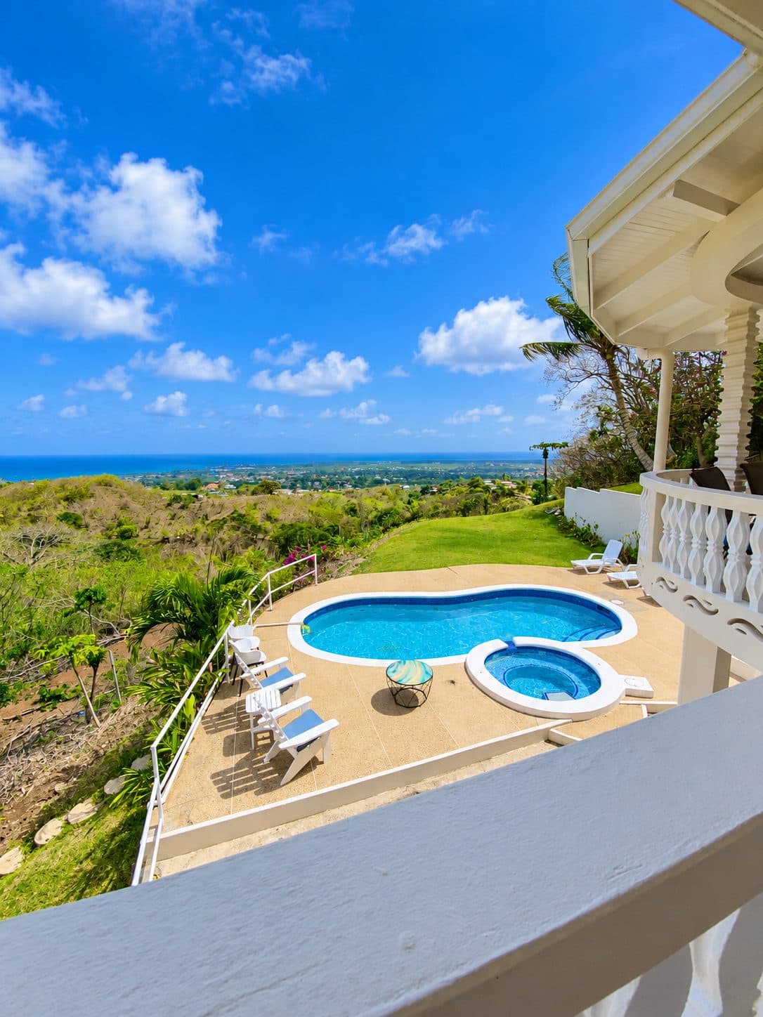 Kidney-shaped pool and spa seen from the balcony, with the Caribbean on the horizon